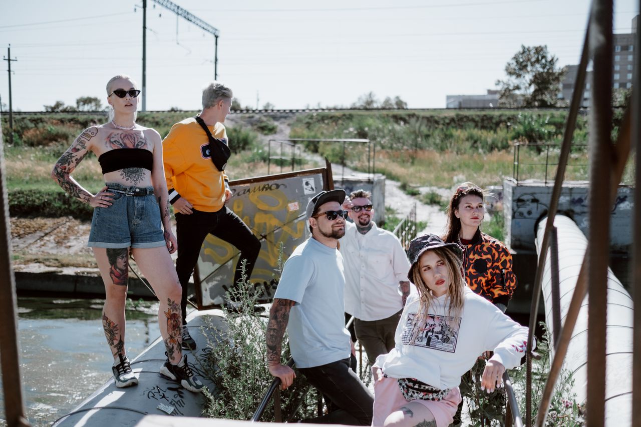 creative Fashionable group posing in streetwear by an industrial outdoor area.